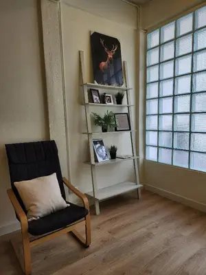 a living room with a chair and a book shelf at Cozy Bangkok Townhouse for 7 Guests, 5-Minute Walk from BTS in Amphoe Phra Khanong