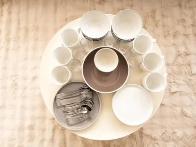 a white plate with bowls and cups on a table at 2 Bedrooms for 4 Guests with Terrace in the Heart of Sathorn in Bangkok