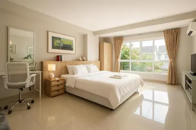 a bedroom with a bed and a desk and a window at Cozy City Retreat in Ekkamai in Bangkok