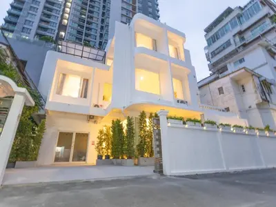a white house with a fence and some buildings at Lovely Studio Room for 2 Guests in the Heart of Sathorn in Bangkok