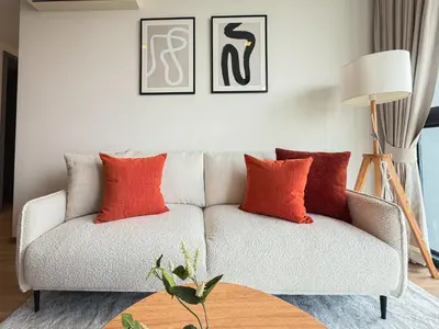 a living room with a couch with orange pillows at Near BTS l Workspace and Kitchen - Pool and Gym l Sontana in Bangkok