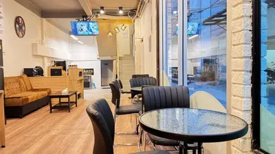 a waiting room with tables and chairs and a couch at Aura Hostel in Bangkok