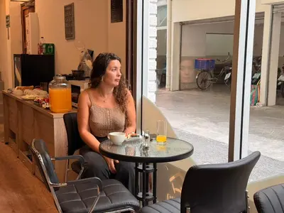 a woman sitting at a table in a room at Aura Hostel in Bangkok