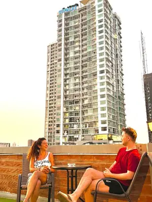 a man and woman sitting at a table with a building at Aura Hostel in Bangkok