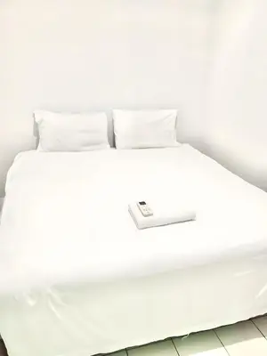a white bed with white sheets and pillows at x Mirt Inn Sukhumvit II - ถนนสุขุมวิท 2 in Bang Kapi