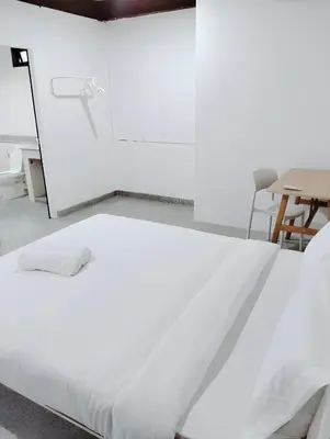 a white bed in a room with a table at x Mirt Inn Sukhumvit II - ถนนสุขุมวิท 2 in Bang Kapi