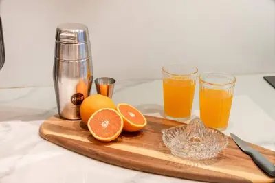 a cutting board with oranges and two glasses of orange juice at Presidential Suite | 5 min BTS, Sun-Room| 159sqm in Khlong Toei