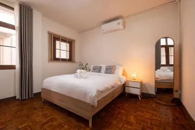 a bedroom with a large bed and a mirror at ThongLor|Spacious 4BR4BA, Fast-WiFi, Netflix, Shop in Khlong Toei