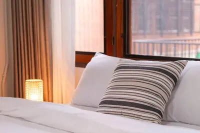 a pillow sitting on a bed in front of a window at ThongLor|Spacious 4BR4BA, Fast-WiFi, Netflix, Shop in Khlong Toei