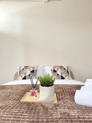 a bed with a table with a potted plant on it at Spacious CityCentre | 500 mbps, King-size, Balcony in Khlong Toei