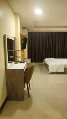 a hotel room with a bed and a desk with a mirror at indra apartments in Bangkok