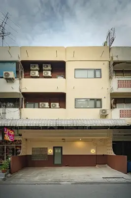 a tall yellow building with two floors and two cars at 2BR APT on 2nd floor for 6 ppl in Bangkok