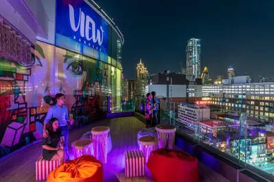 a group of people sitting on a rooftop at night at The Little Apartment in Bangkok