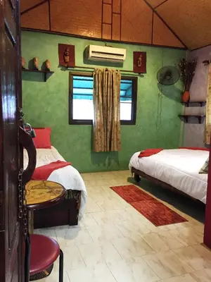 a bedroom with two beds and a table and a chair at Shanti Lodge Bangkok in Bangkok