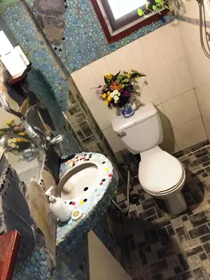 a bathroom with a toilet and a sink with flowers at Shanti Lodge Bangkok in Bangkok