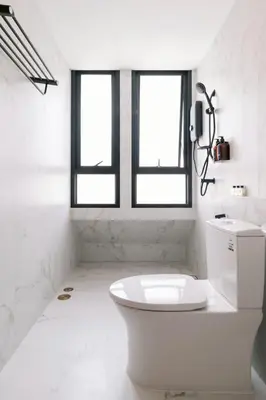 a white bathroom with a toilet and two windows at กรุงไทย โฮสเทล สเตชั่น in Thonhuri