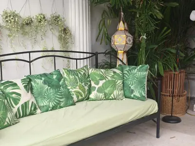 a couch with green and white pillows and a clock at Danita's Home Bangkok in Bangkok