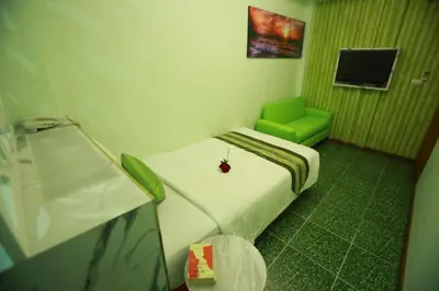 a small room with a bed and a green chair at Lucky Green View in Bangkok