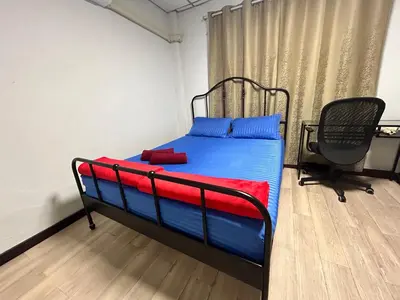 a bedroom with a bed with blue and red sheets and a chair at Wewash Room Laksi - Donmuang Airport ห้องวีวอช หลักสี่ -สนามบินดอนเมือง in Thung Si Kan