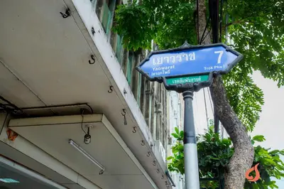 a blue street sign on a pole in front of a building at Pho Place in Bangkok
