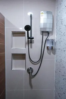 a shower in a bathroom with a hose on a wall at Cozy KingsizeBed เจริญนคร
