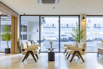 a waiting room with chairs and tables and windows at The Bentley Hotel in Bangkok