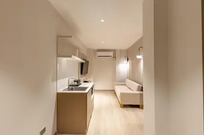 a kitchen with a sink and a couch in a room at The Bentley Hotel in Bangkok