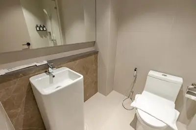 a bathroom with a white toilet and a sink at The Bentley Hotel in Bangkok