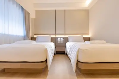 two beds in a hotel room with white sheets at The Bentley Hotel in Bangkok
