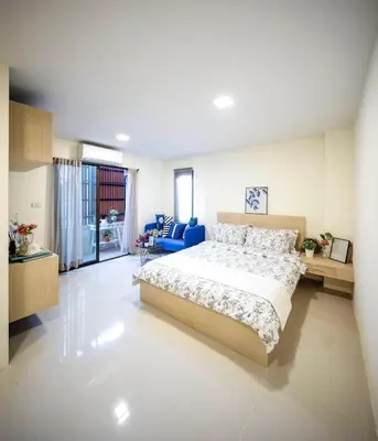 a bedroom with a large bed and a blue chair at Narada Residence in Pak Kret