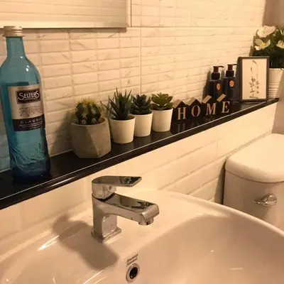 a bathroom sink with a bottle of water and plants at Narada Residence in Pak Kret