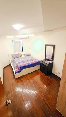 a bedroom with a bed and a mirror on a wooden floor at River View Bangkok Apartment in Bangkok