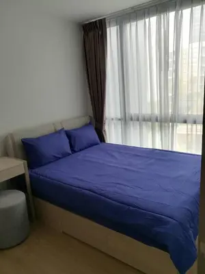 a bed with blue sheets in a room with a window at 1 bed apartment at Phra Khnong in Bangkok