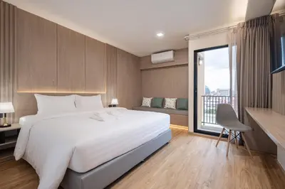 a bedroom with a white bed and a large window at Solyn Hotel in Bangkok