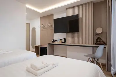 a hotel room with two beds and a desk at Solyn Hotel in Bangkok