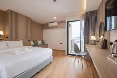 a bedroom with a large white bed and a desk at Solyn Hotel in Bangkok