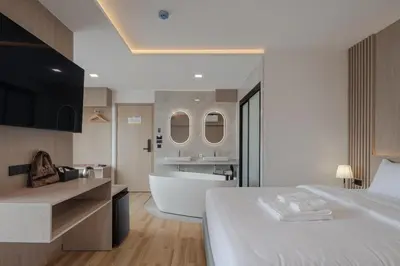 a hotel room with a bed and a bath tub at Solyn Hotel in Bangkok