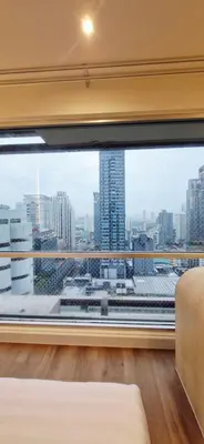a bedroom with a large window with a view of a city at Your Urban Oasis in the Heart of Sukhumvit in Bangkok