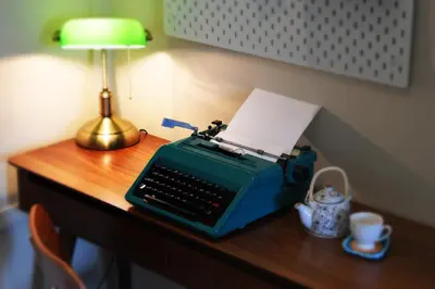 a blue typewriter sitting on a desk with a lamp at Pillow & Paper in Bangkok