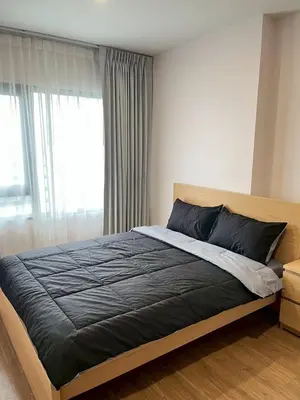 a bedroom with a bed with a black blanket and a window at Stay in near International airport in Bangkok