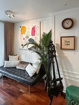 a living room with a black couch and a clock at Prime Classic 1 BR BTS Chidlom 72SQM Langsuan in Bangkok