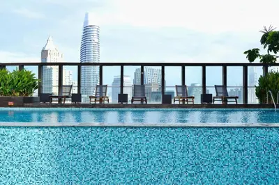 a swimming pool with chairs and a city skyline at Prime Classic 1 BR BTS Chidlom 72SQM Langsuan in Bangkok