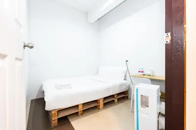 a small room with a bed and a refrigerator at xx The Hidden Khaosan - Rambuttri เดอะ ฮิดเด้น ตรอกข้าวสาร รามบุตรี in Bang Bua Thong Railway Station