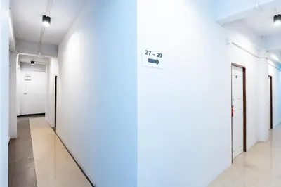 a hallway with white walls and a sign on a wall at xx The Hidden Khaosan - Rambuttri เดอะ ฮิดเด้น ตรอกข้าวสาร รามบุตรี in Bang Bua Thong Railway Station