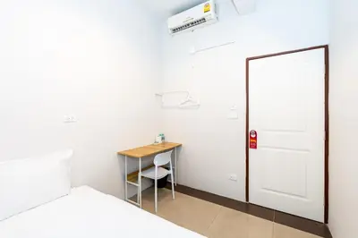 a bedroom with a bed and a desk and a door at xx The Hidden Khaosan - Rambuttri เดอะ ฮิดเด้น ตรอกข้าวสาร รามบุตรี in Bang Bua Thong Railway Station