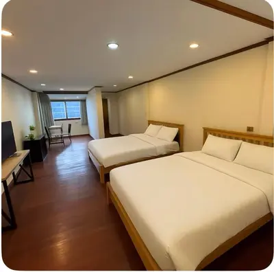 a hotel room with two beds and a desk at Omalaya Bangkok in Samphanthawong