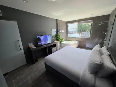 a bedroom with a bed and a tub and a television at HK Villa Resort in Bangkok