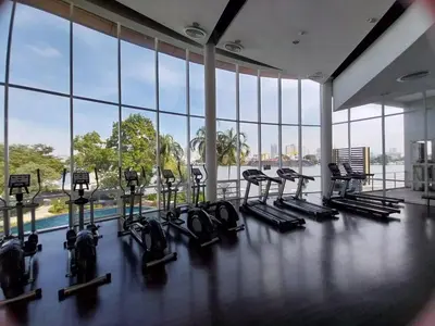 a gym with a row of treadmills and a pool at Riverview Condo Near Icon Siam Hi Speed Internet in Rat Burana