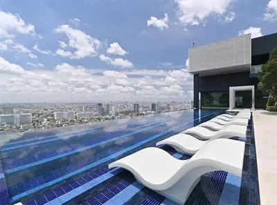 a swimming pool with white lounge chairs on a building at 2 Bedroom Life Ladprao in Bangkok