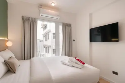a bedroom with a white bed with a tv on the wall at Hotel PaPa Ratchada-Huai Khwang in Bangkok